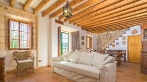 A cozy living room with a sofa, wicker chair, and a staircase leading to another room. - Son Paparra - Villa With Private Pool In Inca (Inca, Illes Balears)