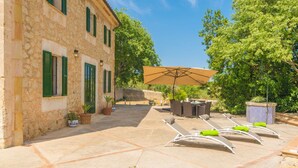 A stone building with green shutters, outdoor seating, and a patio area with lounge chairs and an umbrella. - Son Paparra - Villa With Private Pool In Inca (Inca, Illes Balears)