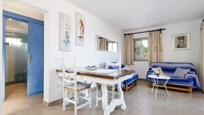 A room with a dining table, chairs, a sofa, and a small white table.