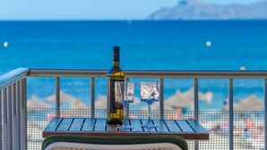 A balcony with a table, a bottle, and two glasses.