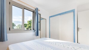 A bedroom with a large bed, a window with curtains, and a door with a blue frame.