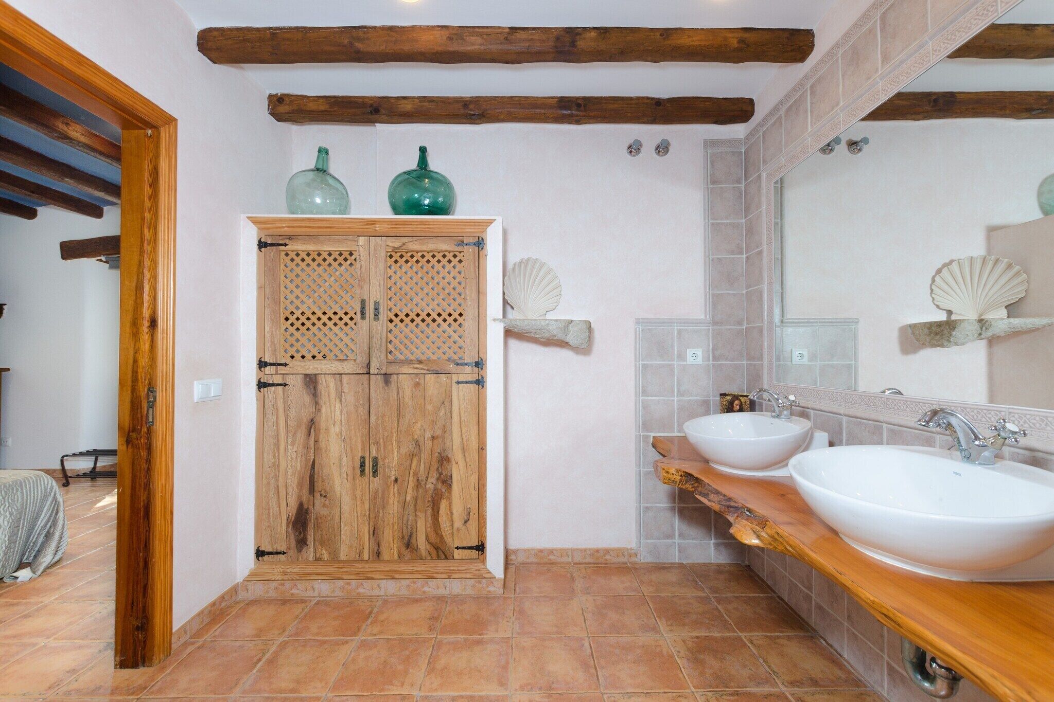A bathroom with wooden cabinets, two sinks, and decorative shells on the wall.