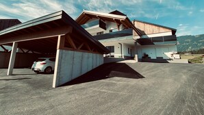 A modern two-story house with a covered driveway and a car parked inside. - Apartment in Saalfelden Near Ski Slopes (Saalfelden am Steinernen Meer)