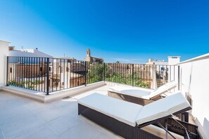 Una terrazza sul tetto con due lettini e vista su un edificio storico con una torre.
