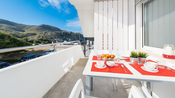 Un balcon avec une table dressée pour deux personnes, offrant une vue sur un paysage montagneux.