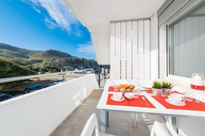 A balcony with a table set for two, overlooking a mountainous landscape.