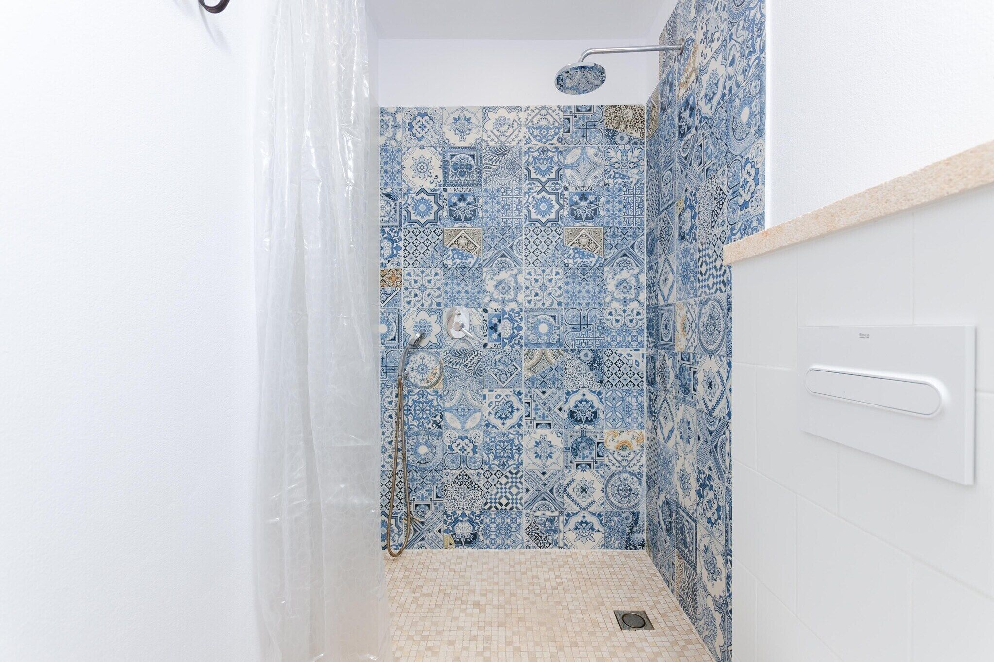 A bathroom with blue and white patterned tiles, a shower, and a white sink.