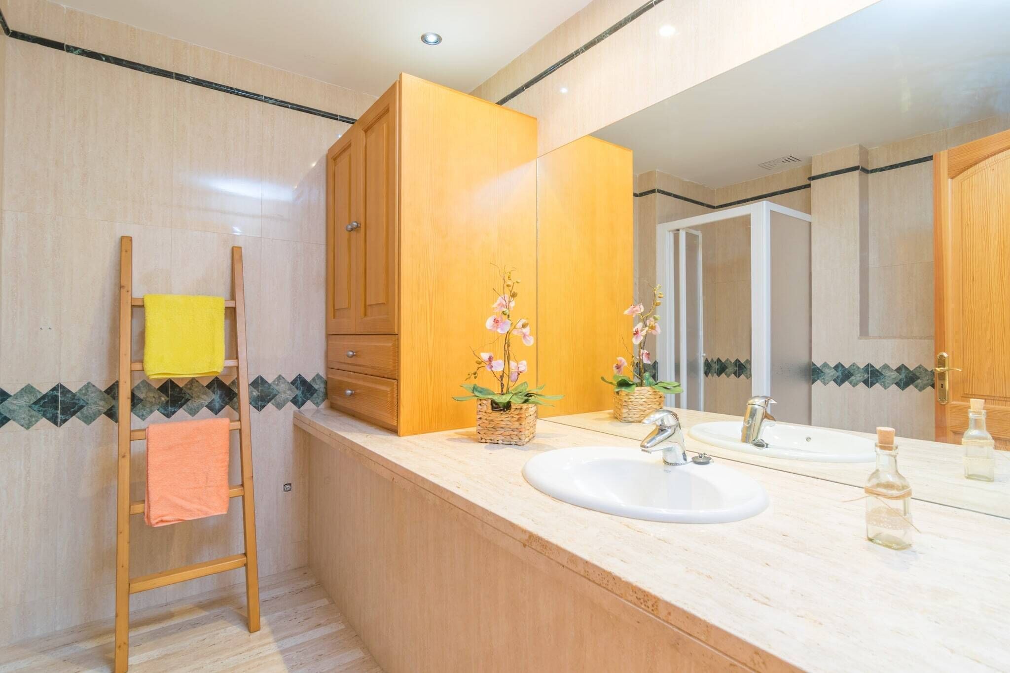 A modern bathroom with a wooden vanity, a large mirror, and a sink.