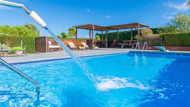 A swimming pool with lounge chairs and a pergola.