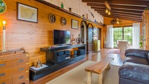 A wooden interior with a TV, wooden furniture, and a bench.