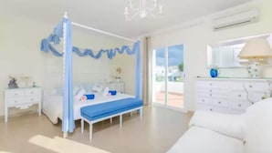 Une chambre à coucher avec un lit à baldaquin, une commode blanche, un miroir et un lustre.