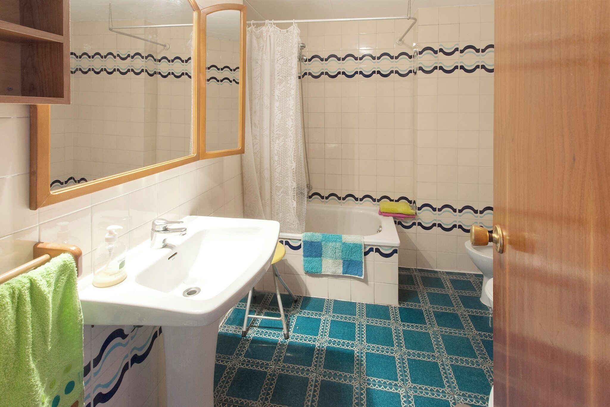 Une salle de bain avec un lavabo, un miroir, une douche et un carrelage décoratif.