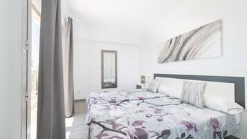 A bedroom with a bed, a large mirror, and a painting on the wall.