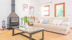 Una sala de estar con chimenea, un sofá, una mesa de centro de vidrio y obras de arte en la pared.