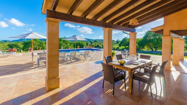 Ein möblierter Außenbereich mit Pool, Esstisch und Stühlen, umgeben von einer Pergola.