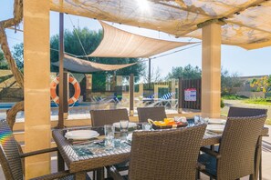 An outdoor dining area with wicker chairs and tables, a pool in the background, and a lifebuoy on the wall. - Sa Tanqueta De Ses Roques - Villa With Pool (Santanyí, Illes Balears)