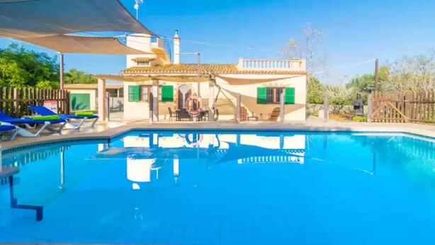 A swimming pool with lounge chairs, a shaded area, and a building with a tiled roof and green shutters. - Sa Tanqueta De Ses Roques - Villa With Pool (Santanyí, Illes Balears)