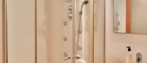 A bathroom with a glass-enclosed shower, a sink, and a mirror.