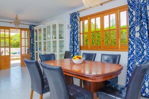 A dining area with a wooden table, black upholstered chairs, a glass cabinet, and patterned curtains.