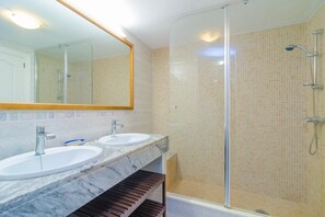 A bathroom with two sinks, a glass shower enclosure, and a large mirror.