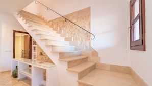 Una escalera con estante de vidrio y pared de piedra.