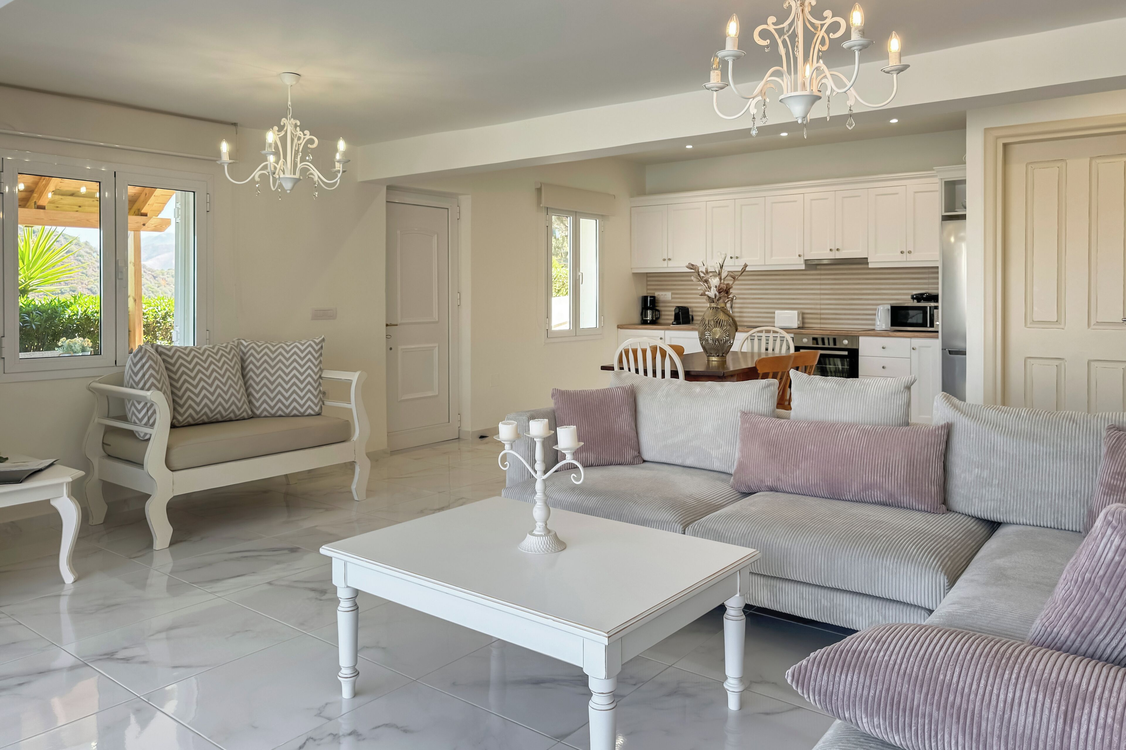 A spacious living area with a white sofa, a coffee table, and a chandelier.