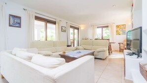 A spacious living room with a large sofa set, a coffee table, and a television. - Ca N'estel - Villa With Private Pool In Cala D'or (Cala D'or, Illes Balears)