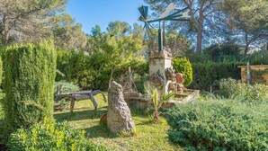 A garden with a windmill, stone structures, and various plants. - Els Pins - Villa With Private Pool In Crestatx (Crestatx , Illes Balears)
