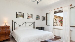 A bedroom with a bed, wooden dresser, and a window with curtains.