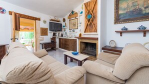 A living room with beige sofas, a TV, a fireplace, and various decorative items on the walls. - Hibiscus - Villa With Private Pool In Crestatx (Crestatx , Illes Balears)