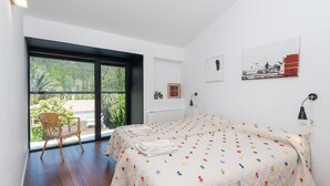 A bedroom with a large sliding glass door leading to a balcony, a bed with a colorful blanket, a chair, and artwork on the walls. - Can Cabrit - Villa With Private Pool In Alaró (AlarÓ, Illes Balears)