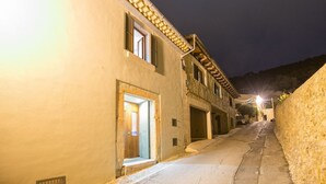A narrow street with buildings on either side, featuring a mix of stone and plaster facades, and a few open doors suggesting residential or commercial use. - Can Cabrit - Villa With Private Pool In Alaró (Alar Ó, Illes Balears)