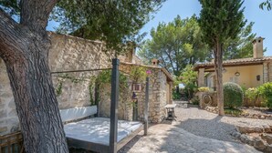 A stone-walled outdoor seating area with a bench, surrounded by trees and a gravel path. - Can Reure - Villa With Private Pool In Inca (Inca, Illes Balears)