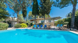 A swimming pool with lounge chairs and umbrellas, surrounded by trees and a stone building. - Can Reure - Villa With Private Pool In Inca (Inca, Illes Balears)