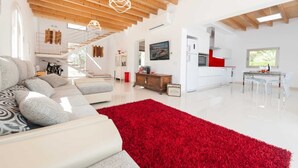 Un vaste espace de vie agrémenté d’un tapis rouge, d’un canapé et d’une table à manger avec des chaises.