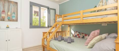 A bunk bed room with a staircase, a window, and a cabinet.