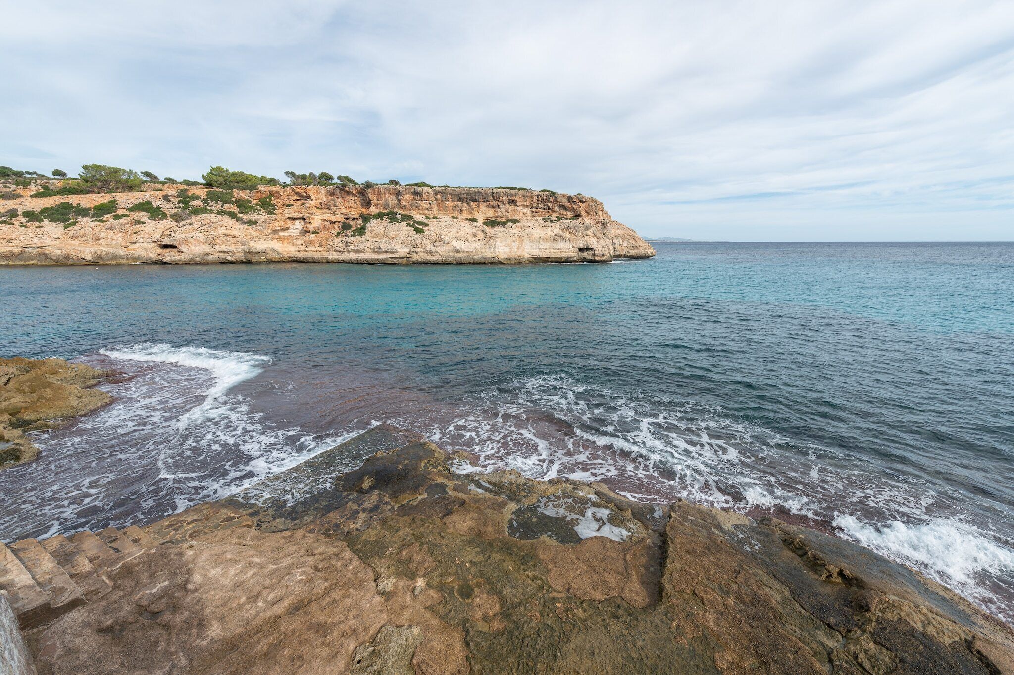 A coastal landscape with rocky cliffs and calm sea.