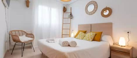 A neatly arranged bedroom with a bed, bedside table, lamp, and a chair.