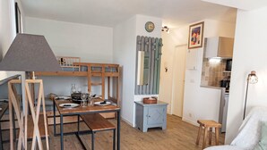 Un espacio habitable compacto con comedor, literas, kitchenette y una pequeña zona de estar.