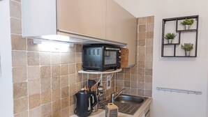 Cocina compacta con microondas, hervidor y una pequeña caja de bienvenida.