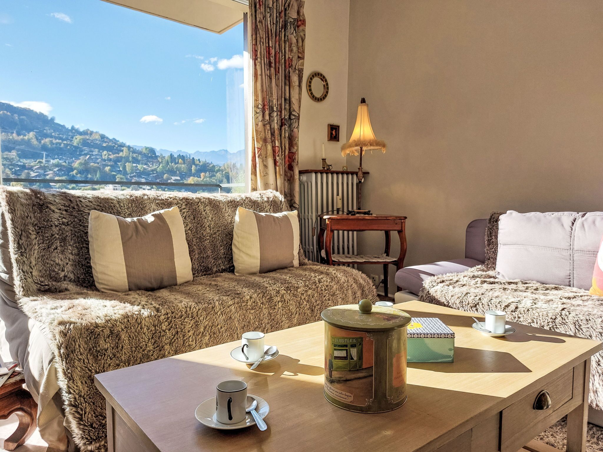 Una sala de estar acogedora con un sofá, una mesa con un bote y vistas a un paisaje montañoso.