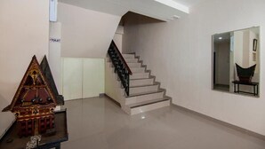A modern interior with a staircase, a small model house, and a mirror on the wall. - Hotel Wisata Samosir By Helocus (Samosir)