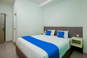 Une chambre d’hôtel avec un grand lit, une literie blanche et bleue, une tête de lit en bois et une table de chevet avec une lampe.