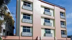 A multi-story building with balconies, a flat roof, and a clear sky. - Hotel Wisata Samosir By Helocus (Samosir)