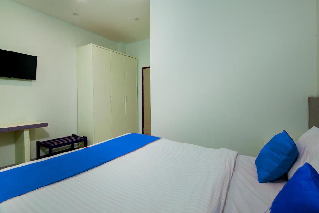 A bedroom with a bed, a desk, and a wardrobe.