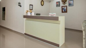 A hotel reception area with a reception desk, framed pictures on the wall, a clock, and a sign indicating the hotel name. - Hotel Wisata Samosir By Helocus (Samosir)