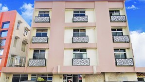 A multi-story building with balconies, a parking lot, and a clear blue sky. - Hotel Wisata Samosir By Helocus (Samosir)