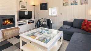 Un salon moderne avec une cheminée, un téléviseur, un canapé et une table basse sur laquelle sont posés des magazines.