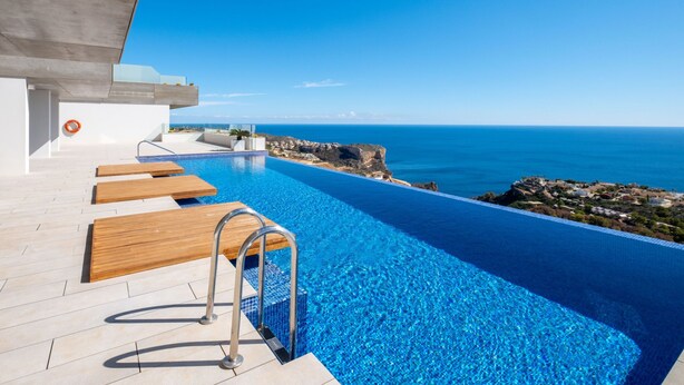 An infinity pool with a clear view of the ocean and rocky coastline.