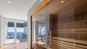 A modern spa area with wooden flooring, glass doors, and a view of the sea.